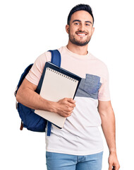 Young handsome man wearing student backpack and notebook looking positive and happy standing and...
