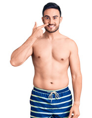 Fototapeta premium Young handsome man wearing swimwear pointing with hand finger to face and nose, smiling cheerful. beauty concept