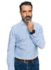 Fototapeta premium Middle aged man with beard wearing business shirt looking confident at the camera smiling with crossed arms and hand raised on chin. thinking positive.