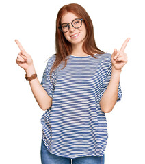 Young read head woman wearing casual clothes and glasses smiling confident pointing with fingers to different directions. copy space for advertisement