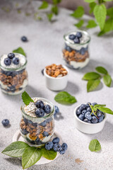 Homemade granola with greek yogurt, maple syrup and fresh blackberries and blueberries in glasses