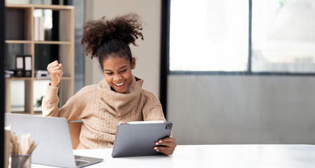 Happy african woman employee in joyful happiness on computer for win, prize or good news at workplace