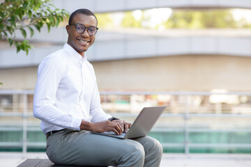 Portrait Of Handsome Black Businessman In Eyeglasses Working On Laptop Outdoors