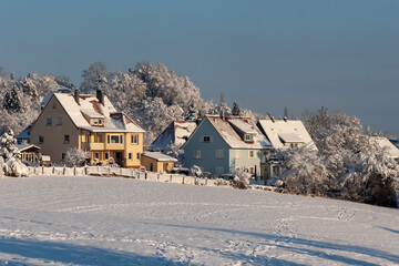 Beautiful winter in a European village - view of a snow-covered field against the backdrop of country houses