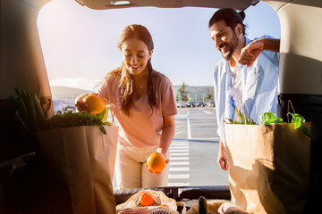 Arab couple admiring groceries in trunk during sunset