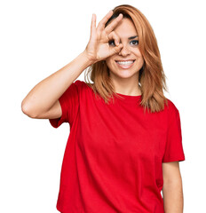 Fototapeta premium Hispanic young woman wearing casual red t shirt doing ok gesture with hand smiling, eye looking through fingers with happy face.