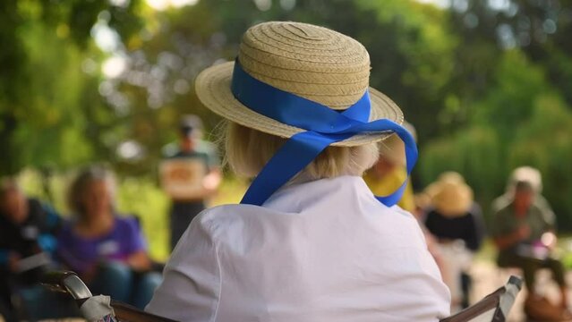 Lady sitting in the park in a hat with a blue ribbon 