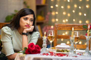 worried sad girl waiting for boyfriend at candlelight dinner arrangement or planning - concept of date night disappointment, relationship problems and valentines day planning