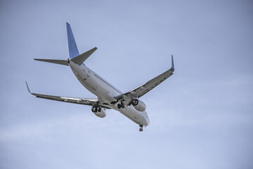 passenger plane with landing gear deployed approaching the runway on a sunny day