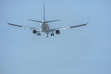 Rear view of a passenger jet with landing gear deployed approaching the runway