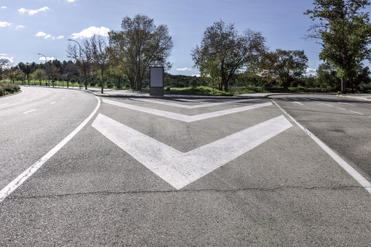 Road with road paint marks next to an urban park with two forks