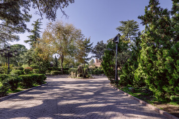 A scene of the water jets of a small decorative fountain on a walking path of an estate with a luxury single-family home