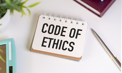 Text Code of Ethics on a white sticker with office stationery background. Flat lay on business,...