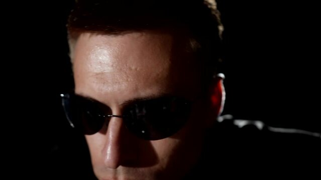 cool man with black sunglasses on eyes sitting on motorcycle in darkness, portrait of rider