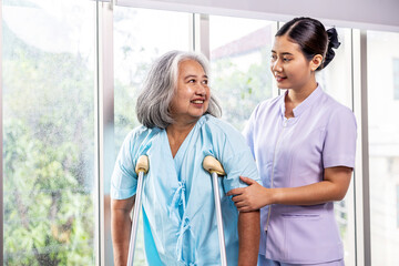Female nurse helping elderly female with walking crutches. Professional care for disabled patients,  Disable old woman trying to walk with the assistance aid of female doctor, disability