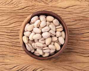 Salted roasted pistachios on a bowl over wooden table
