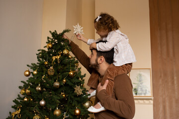 happy father and little daughter on his head decorating Christmas tree
