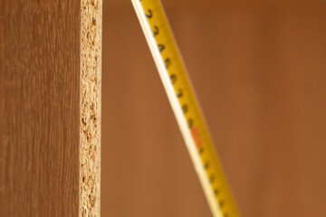 Tape measure and the end of a wooden board. Measurement in centimeters and millimeters. Furniture assembly