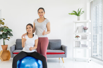 Smiling personal trainer and client give thumbs up in home workout