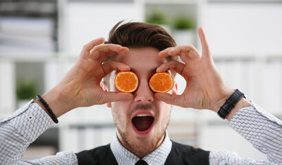 Male hands hold a cut fruit at eye level instead of glasses. The theme of a healthy diet for...