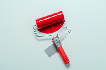 Paint roller affixed with gray duct tape to blue wall with spreading red paint. Creative renovation...