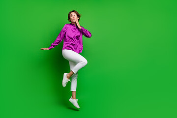 Fototapeta na wymiar Full length portrait of impressed pretty person jumping look empty space advert isolated on green color background