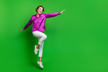 Fototapeta na wymiar Full length portrait of overjoyed lovely person jumping flying empty space ad isolated on green color background