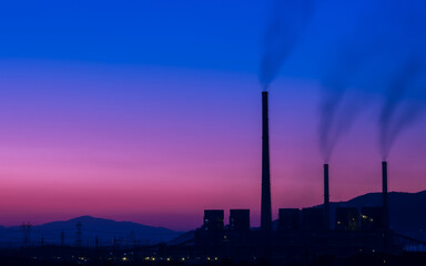 Dirty fumes from factory chimneys. Electricity generation plant at dawn. Industrial buildings...