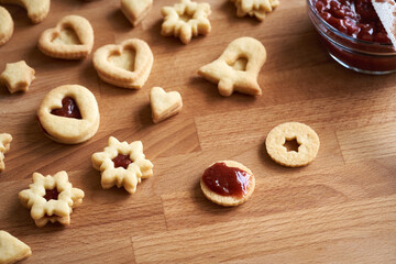 Filling homemade Linzer Christmas cookie with red strawberry marmalade