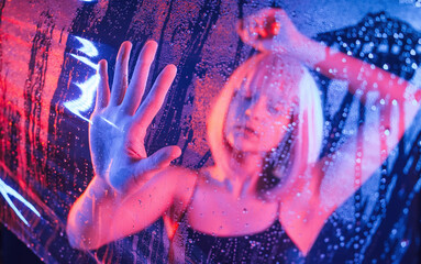 Hands are on the surface. Stylish woman with white hair is behind wet transparent plastic sheet