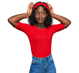 Beautiful african young woman wearing casual clothes doing bunny ears gesture with hands palms...