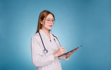 Young asian doctor wear medical uniform lab coat and stethoscope on blue background. Smiling female...