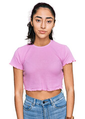 Hispanic teenager girl with dental braces wearing casual clothes relaxed with serious expression on...