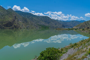 Naklejka na ściany i meble reflection of mountains in the lake and white clouds in the blue sky