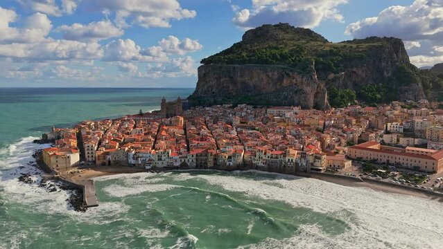 Aerial shot of Cefalu - medieval village of Sicily island. Flying above old town with orange roofs at the foot of the mountain - Cefalu, Sicily, Italy
