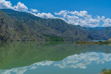 reflection of mountains in the lake and white clouds in the blue sky