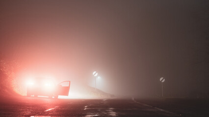 A car parked with it's door open. On the side of the road. On a spooky, eerie, foggy, winters night.