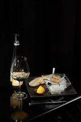 Pike fish caviar, on ice, with croutons, lemon, on a transparent dish, on a dark background