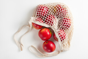 Seasonal red apples in a string bag on a white background in a eco-friendly bag