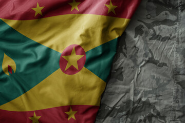 waving flag of grenada on the old khaki texture background. military concept.