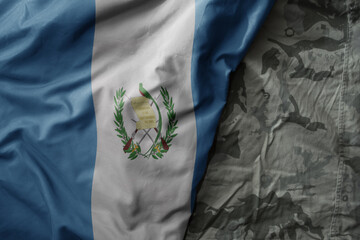waving flag of guatemala on the old khaki texture background. military concept.