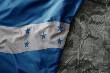 waving flag of honduras on the old khaki texture background. military concept.