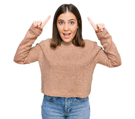 Young beautiful woman wearing casual clothes smiling amazed and surprised and pointing up with fingers and raised arms.