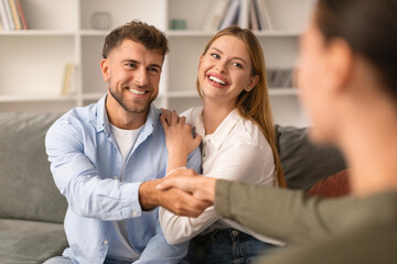 Joyful millennial spouses share a handshake with their therapist indoors
