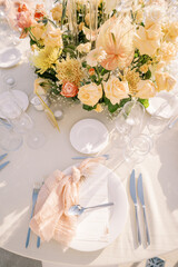Festive menu lies on a plate near a knotted napkin in front of a colorful bouquet of flowers. Top...