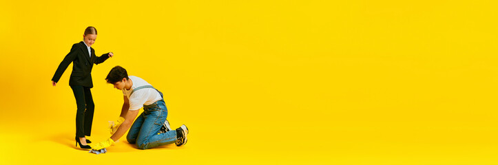 Banner. Responsible little girl steps over janitor against vivid yellow background with negative...