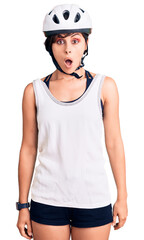 Beautiful young woman with short hair wearing bike helmet scared and amazed with open mouth for surprise, disbelief face
