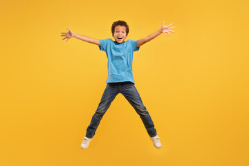 Fototapeta na wymiar Joyful boy jumping, light blue shirt, full length