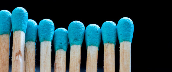 a row of blue matches on black background. Concept