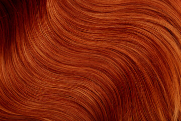 Red hair close-up as a background. Women's long orange hair. Beautifully styled wavy shiny curls....